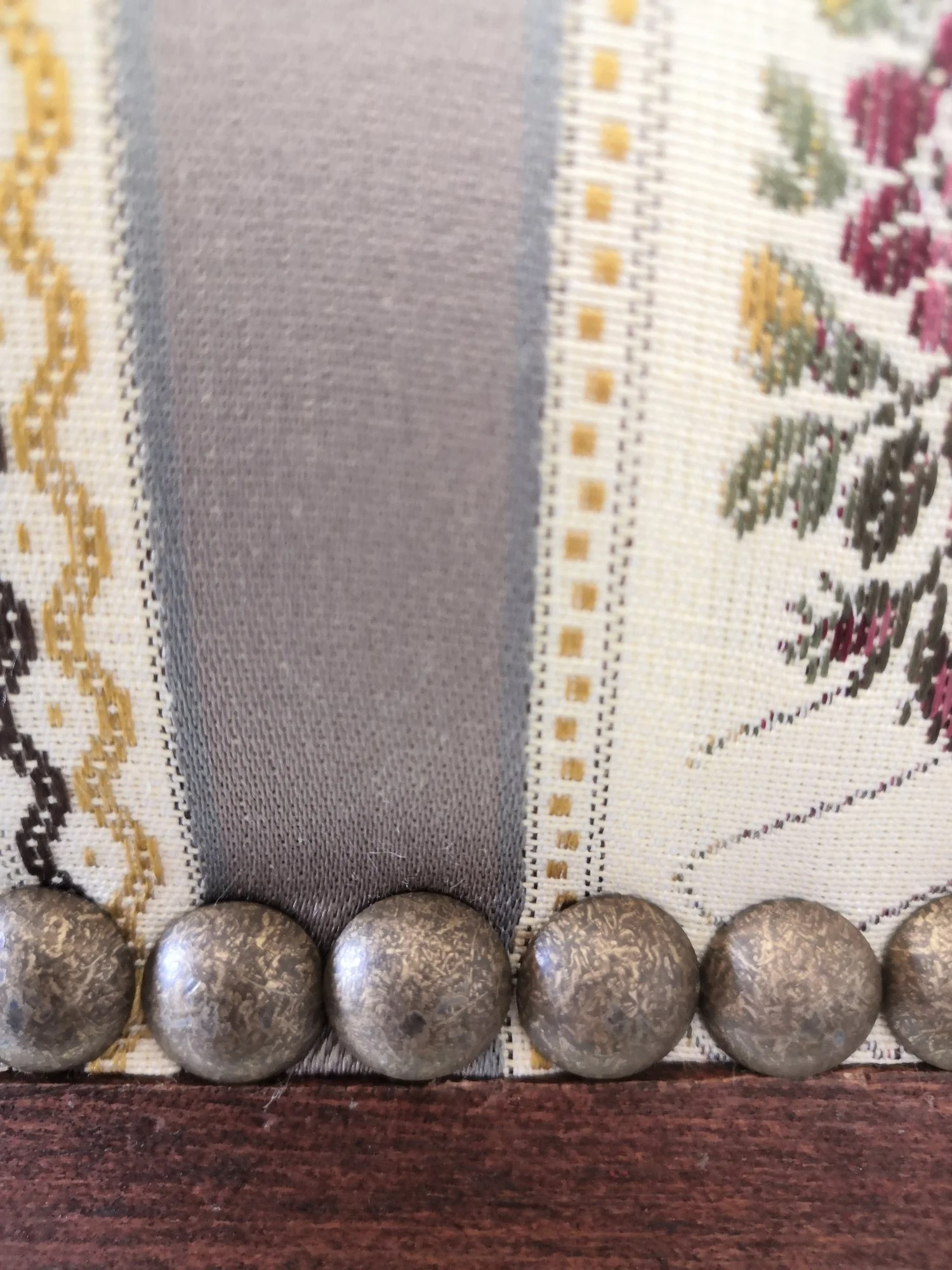 Clous de tapissier en laiton sur un tissu rayé fleuri